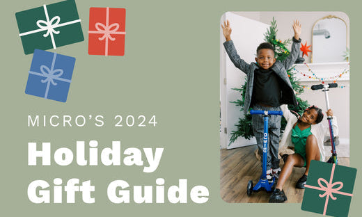Excited boy and girl pose with two Micro Scooters in front of a Christmas tree.