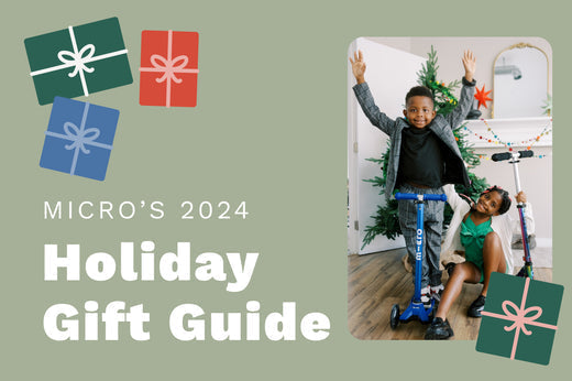 Excited boy and girl pose with two Micro Scooters in front of a Christmas tree.