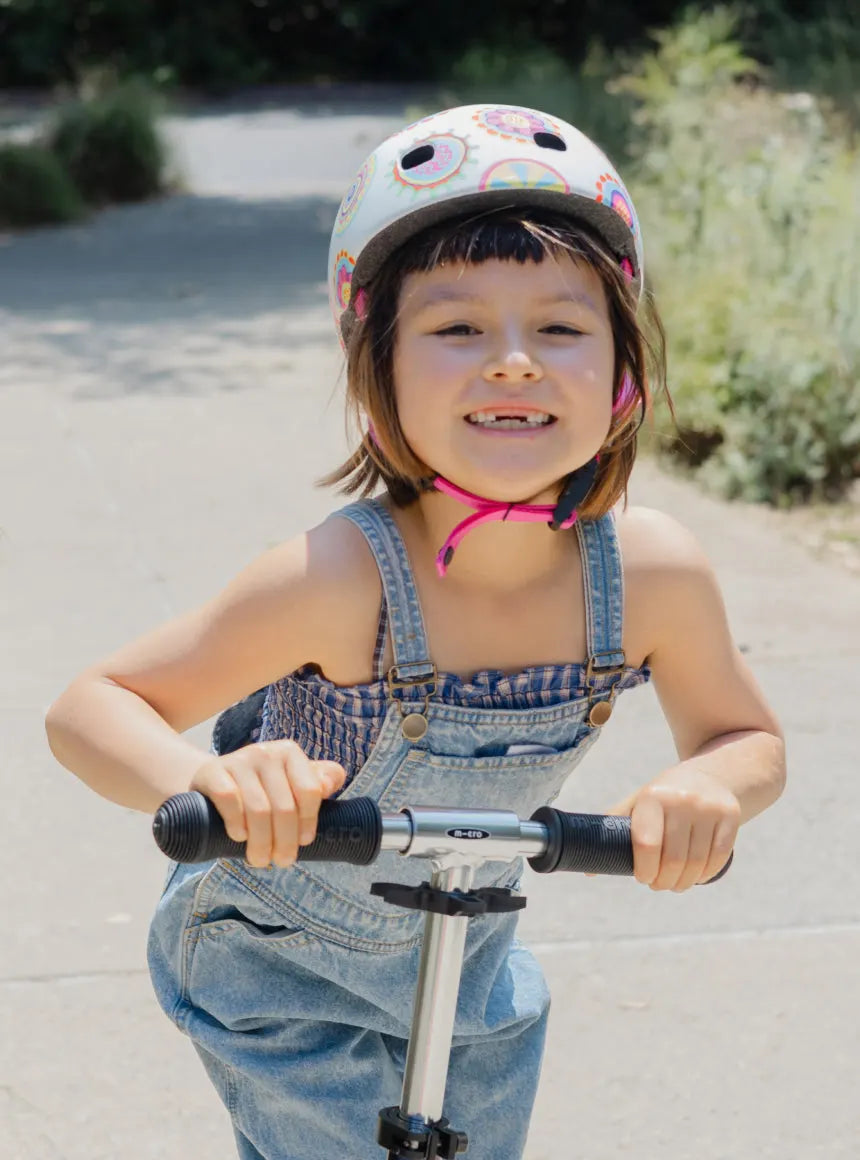 Older child riding a Micro Kickboard 2-wheeled scooter on a paved path — ideal for big kids gaining scooter confidence.