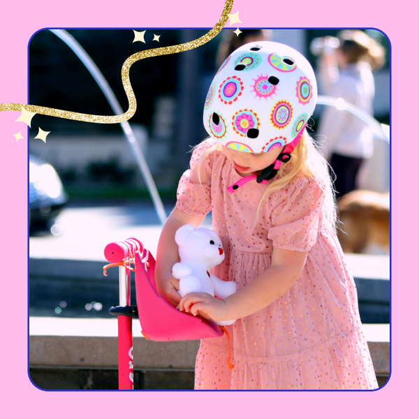 A young girl puts her stuffed animal into the Micro ScootaSeatz on her Micro scooter. 