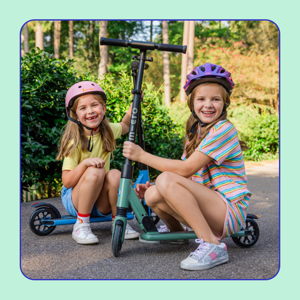 Two girls smile and pose with their Micro Sprite Suspension Scooters.
